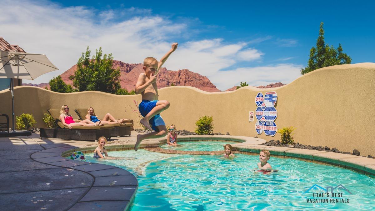 Kid jumping into private swimming pool at family reunion vacation home..